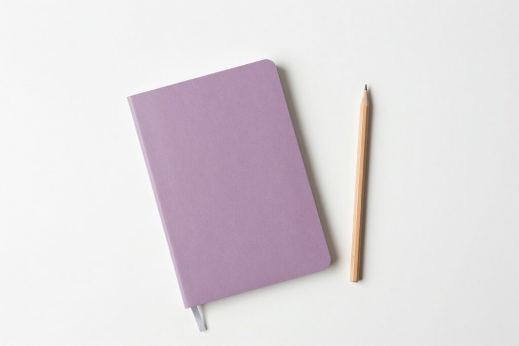 A closed mauve notebook beside a wooden pencil on a white surface